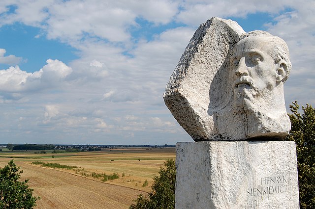 Pomnik Henryka Sienkiewicza w Okrzei, w głębi widoczna Wola Okrzejska, fot. Marcin Białek - Praca własna, wikimedia (na licencji CC BY-SA 4.0)